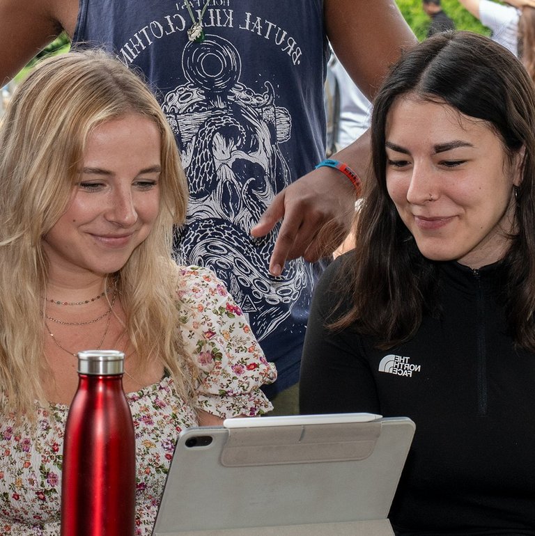 3 Studierende sitzen vor einem Tablet