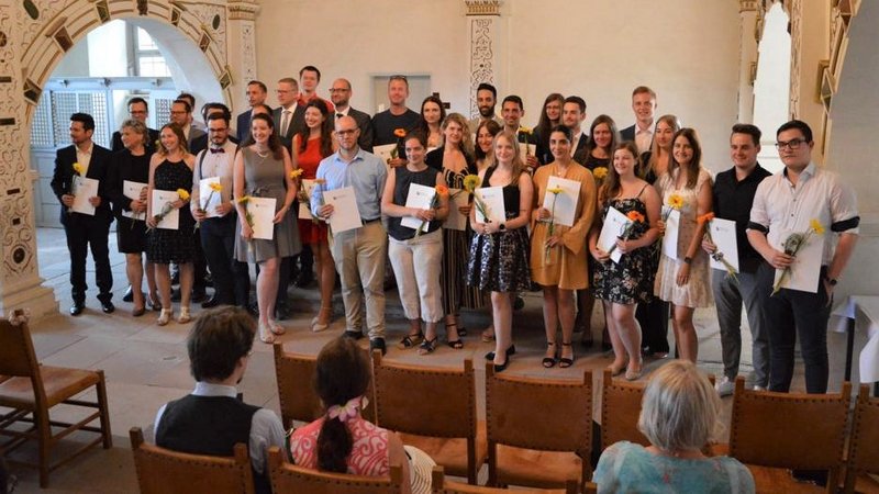 Stolze Absolventen der Fakultät Wirtschaftsrecht mit ihren Zeugnissen in der Schlosskirche von Schloss Wilhelmsburg in Schmalkalden