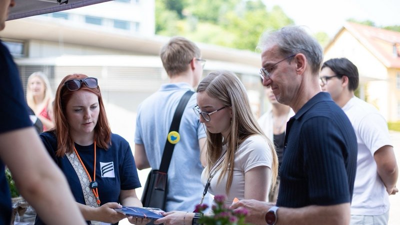 Schülerin mit Eltern am Infostand