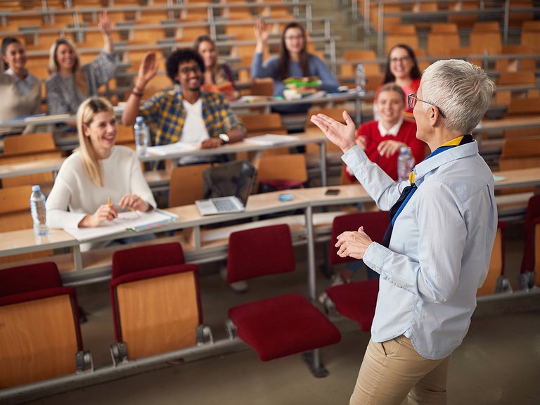 Dozentin steht im Hörsaal vor Studierenden