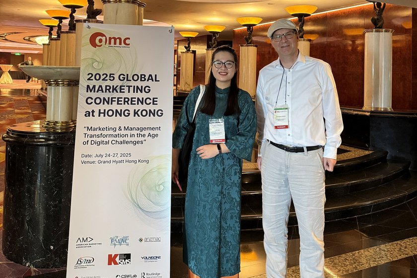Prof. Dr. Sebastian Ullrich und Phuong Thanh Bui vor einem Banner der Global Marketing Conference in Hongkong