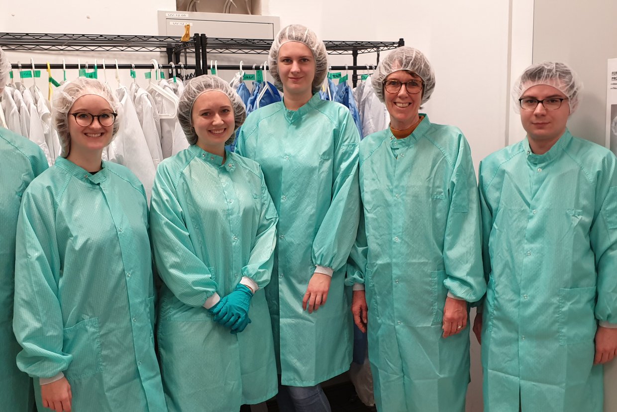 Gruppenfoto: Frau Prof. Dr. Störmann mit Studierenden im Produktionsbereich der Opvius GmbH. Alle tragen helle Schutzkleidung und Haarnetz.