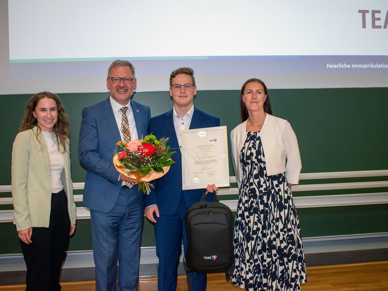 Vier Personen mit Blumen und Urkunde