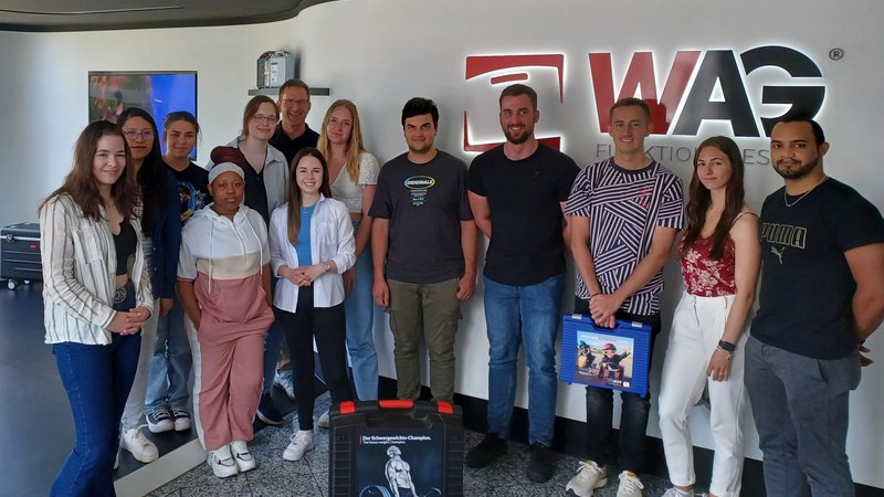 Zwölf Studierende und Prof. Dr. Dornieden im Gruppenfoto vor dem WAG-Logo