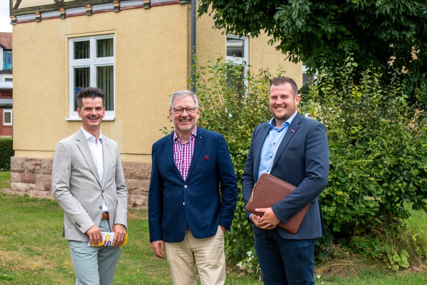 Drei Männer vor einem Haus