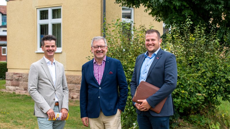 Drei Männer vor einem Haus