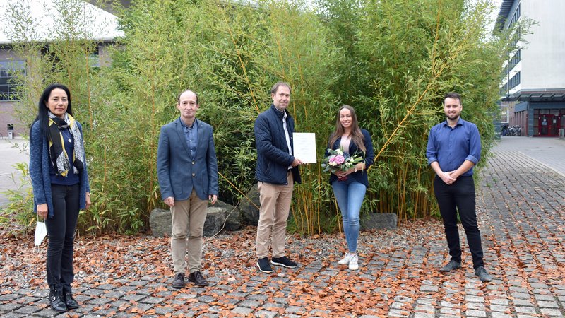 Preisträgerin mit Laudatoren auf dem Campus