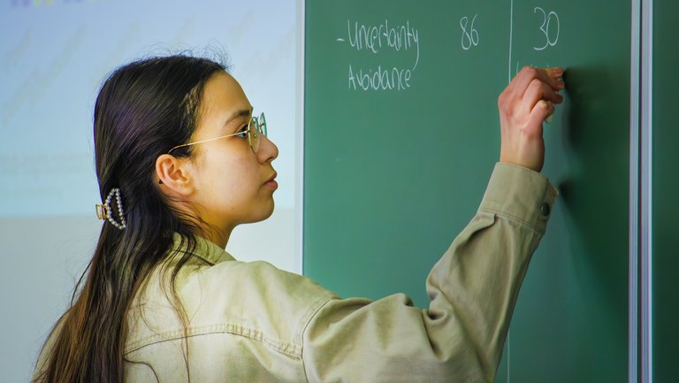 Studentin schreibt an eine Tafel