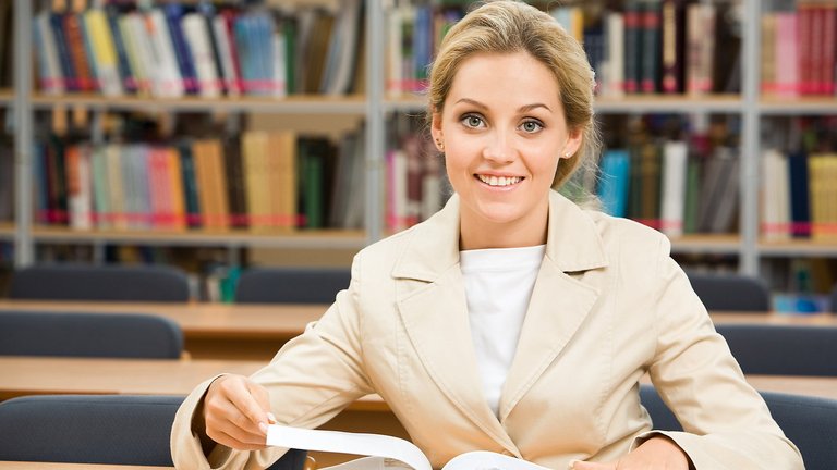 Studierende des VWL-Studiums in Bibliothek mit geöffneten Buch.