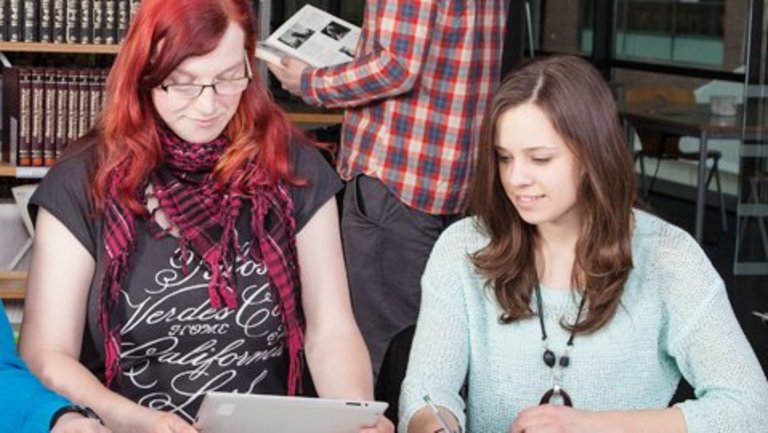 Menschen in einer Bibliothek sitzen vor Computern