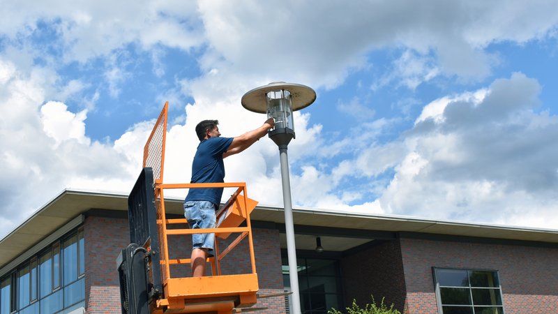Der technische Mitarbeiter René Merx tauscht konventionelle Leuchtmittel gegen LED-Lampen auf dem Campus der Hochschule.