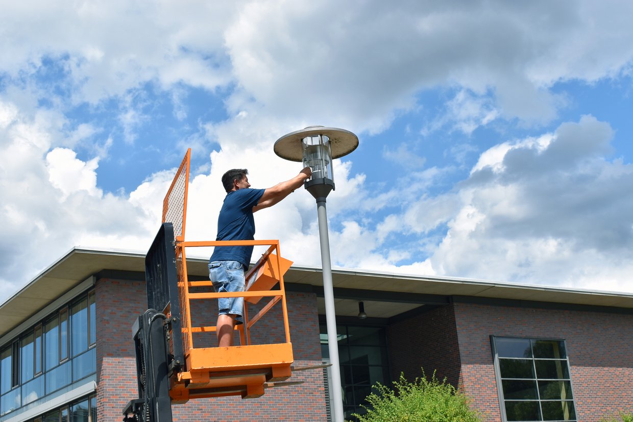 Der technische Mitarbeiter René Merx tauscht konventionelle Leuchtmittel gegen LED-Lampen auf dem Campus der Hochschule.