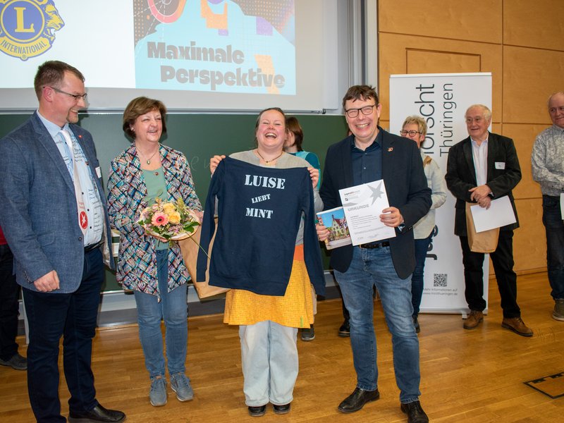 Lachende Frau mit Pullover in der Hand