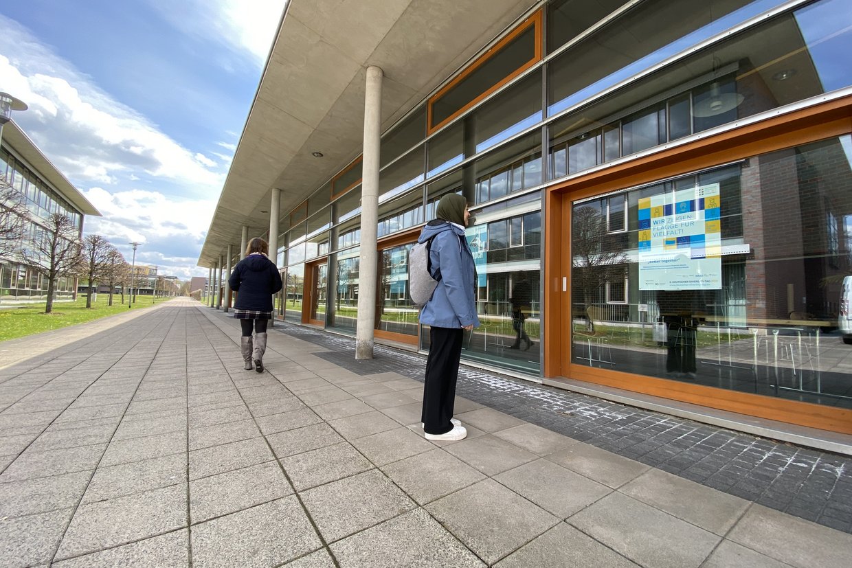 Studentin schaut sich ein Plakat an der Mensa an