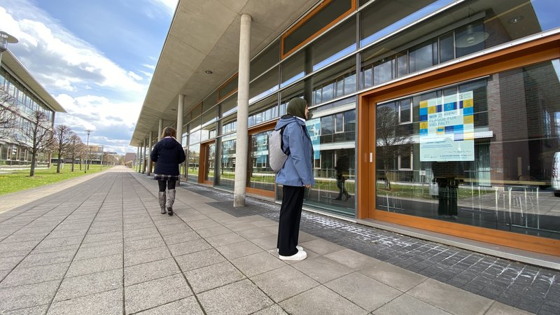 Studentin schaut sich ein Plakat an der Mensa an