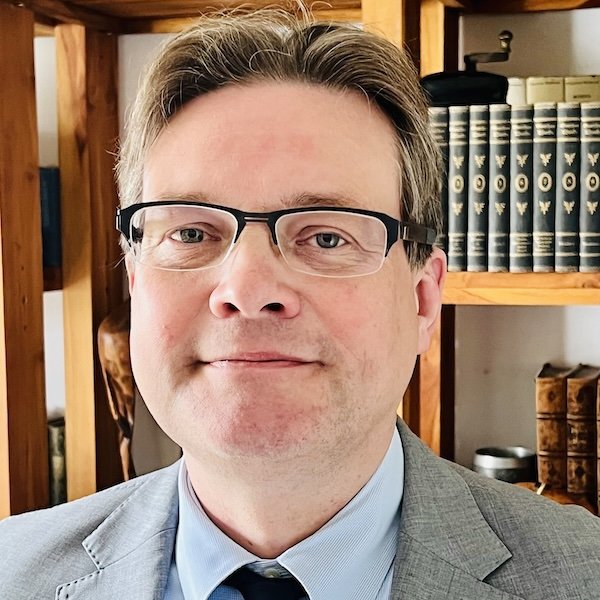 Prof. Müller vor einem Bücherregal