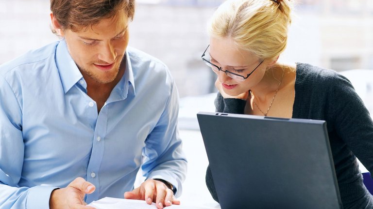 Mann und Frau sitzen vor einem Laptop und lesen Buch 