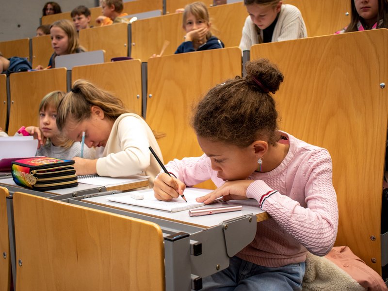 Kinder schreiben in der Vorlesung mit