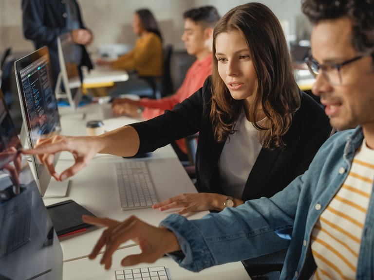 Studierende vor dem Rechner erklären sich gegenseitig eine Aufgabe