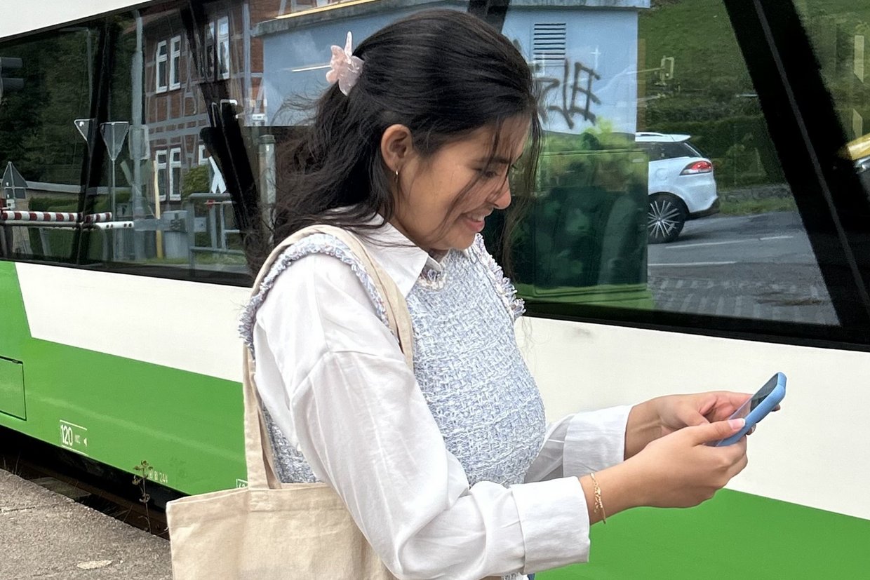 Frau am Handy vor einem Zug