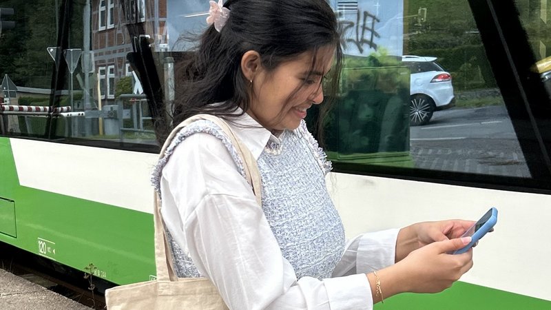 Frau am Handy vor einem Zug