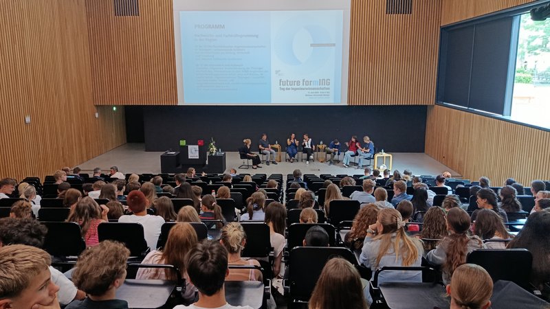 Menschen schauen auf Podium im Hörsaal