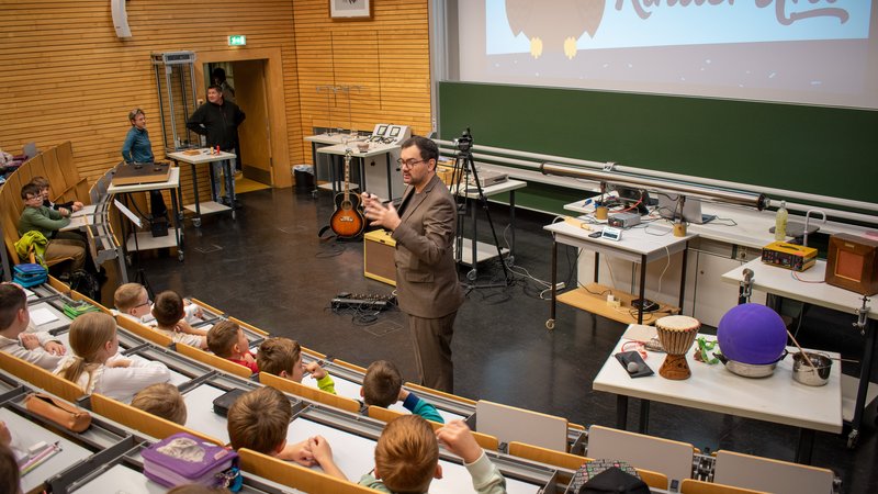 Mann steht vor Kindern im Hörsaal