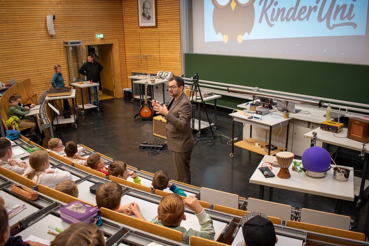Mann steht vor Kindern im Hörsaal