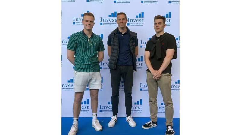 Mats Lemke, David Mahnkopf und Elias Mendel stehen vor einer "Invest"-Plakatwand