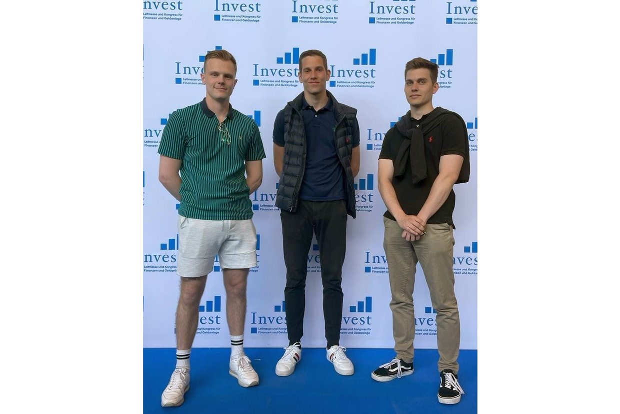 Mats Lemke, David Mahnkopf und Elias Mendel stehen vor einer "Invest"-Plakatwand