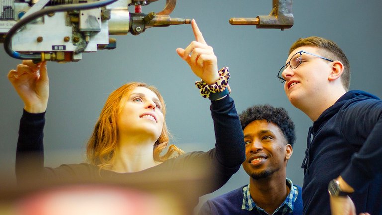 Studentin zeigt auf Maschine