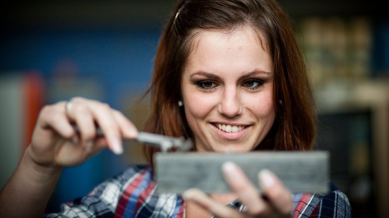 Studentin misst ein Werkstück mit einer Schieblehre aus