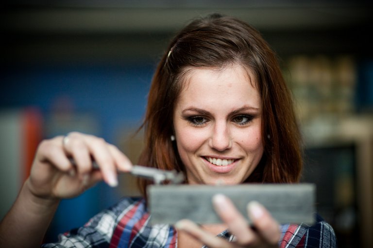 Studentin misst ein Werkstück mit einer Schieblehre aus