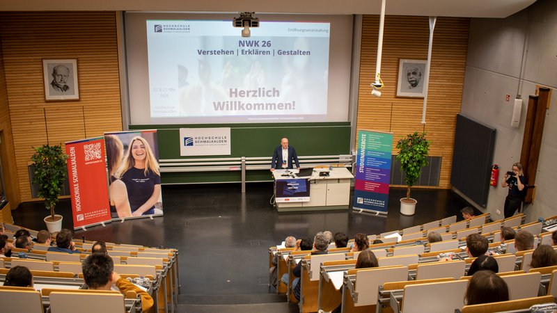 Professor begrüßt Teilnehmer im Hörsaal