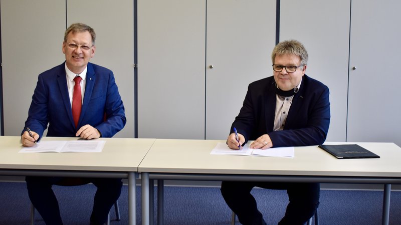 Hochschulpräsident Prof. Gundolf Baier und Schulleiter Jürgen Haaß unterzeichnen den Kooperationsvertrag.