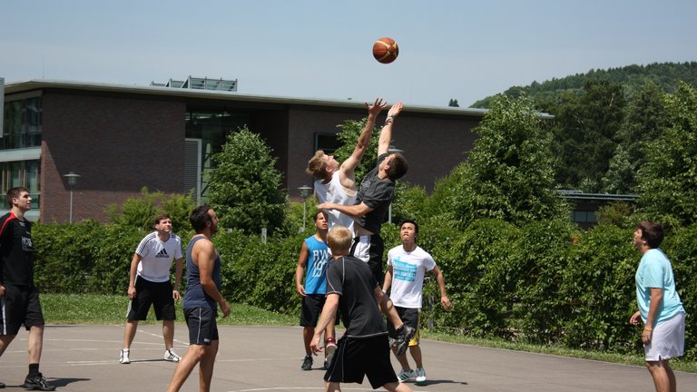 Studierende spielen Basketball auf dem Campus der Hochschule