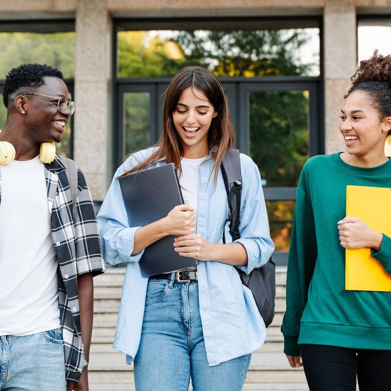 Studierende verlassen ein Hörsaalgebäude und reden miteinander
