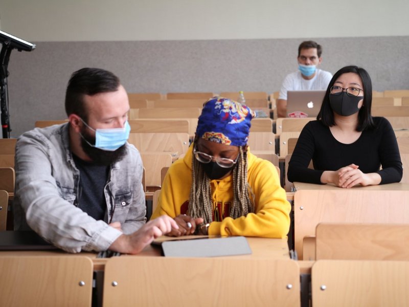2) Unsere beiden studentischen Hauptdarsteller sowie zwei Studierende im Hintergrund im Hörsaal C101